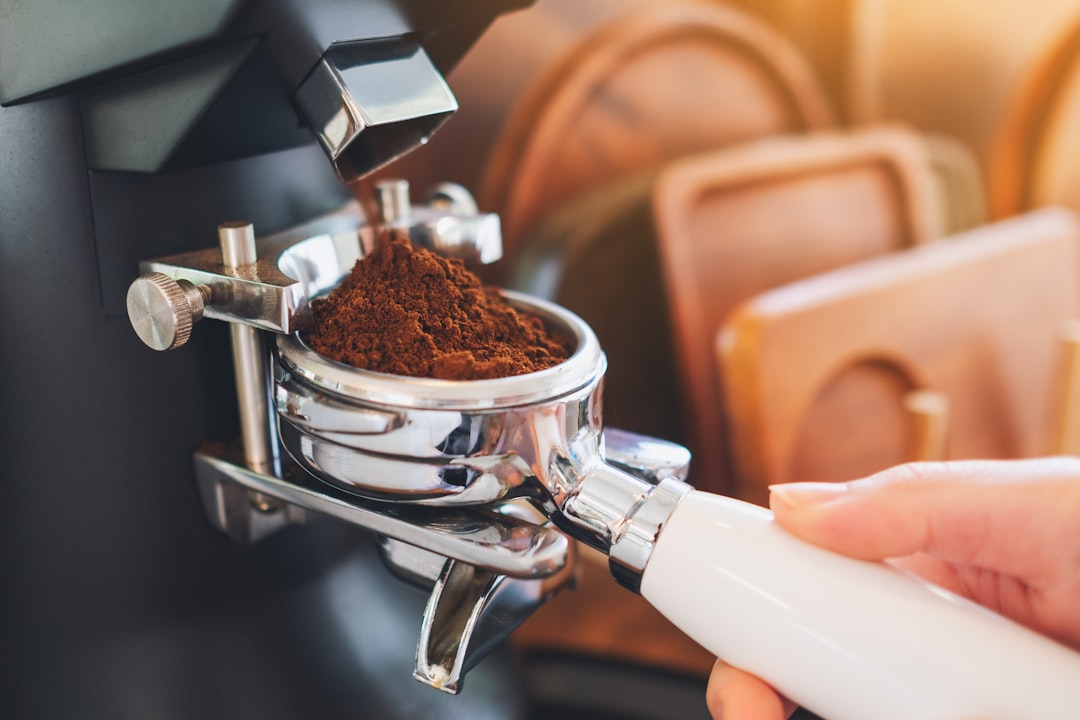 Freshly ground coffee filling a portafilter basket beneath an electric single-dose grinder chute