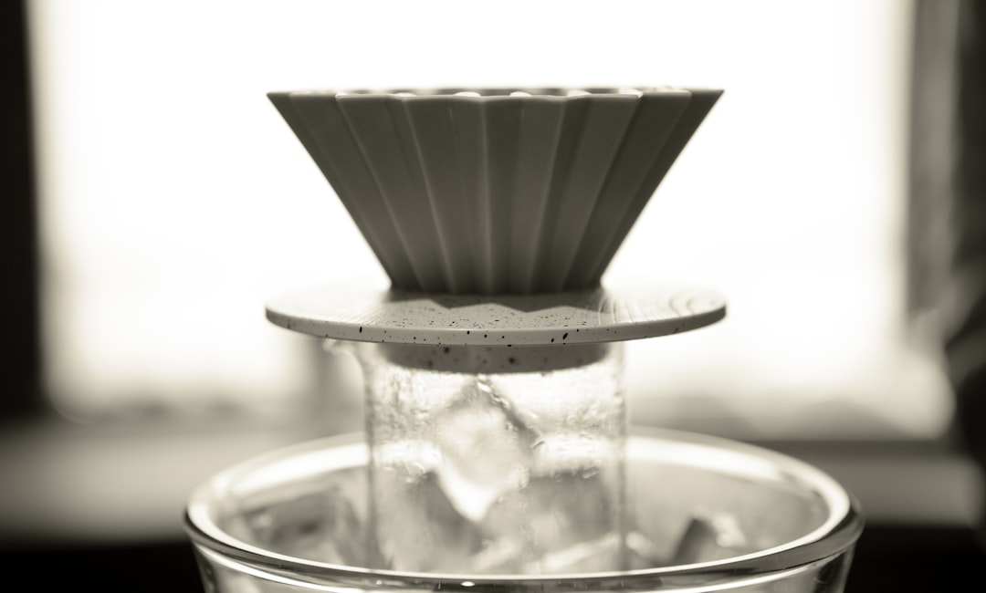 A fluted ceramic pour-over dripper resting on top of a glass carafe packed with ice cubes, set up to brew directly over the ice