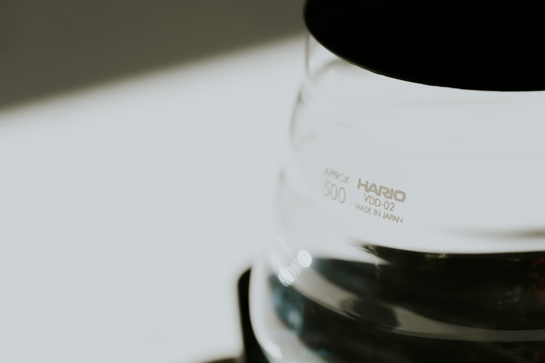 Close-up of a Hario glass coffee vessel etched with 'HARIO VDD-02 Made in Japan,' backlit against a white surface