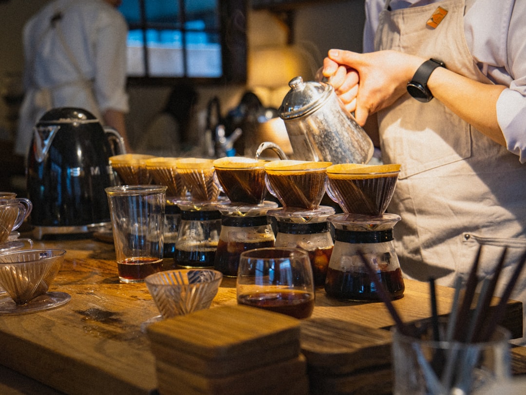 a person pouring a cup of tea on top of a wooden table