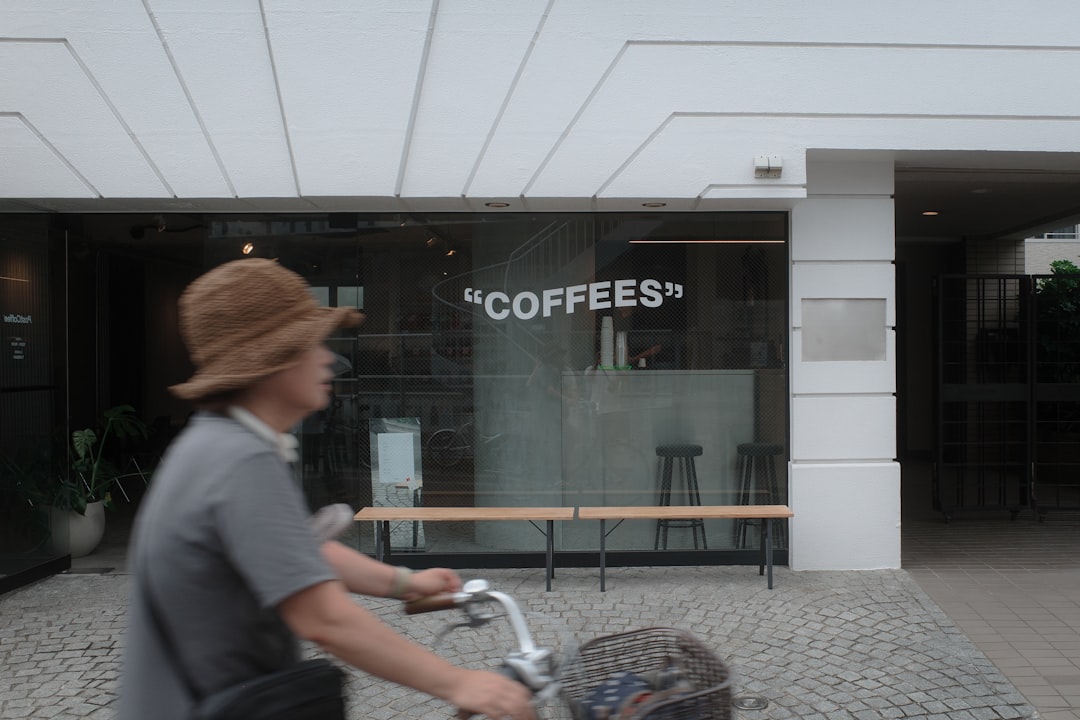 A man riding a bike past a coffee shop — pre-batched espresso debate in specialty coffee