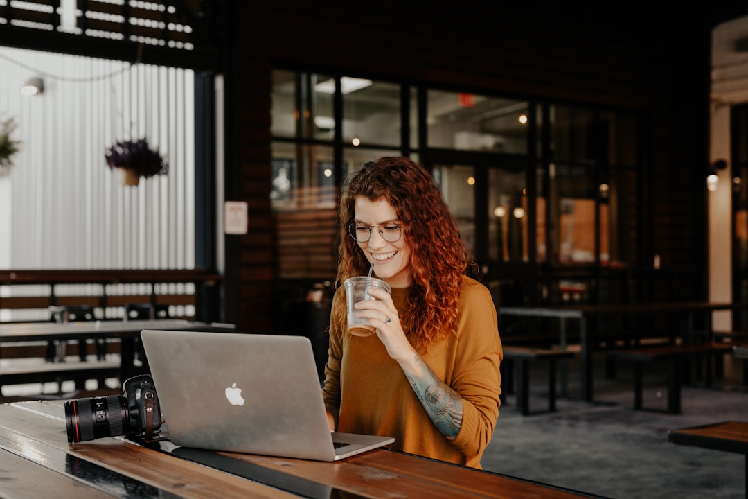 Woman working on a laptop at a café table, coffee cup within reach